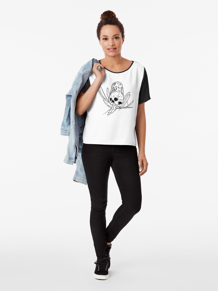 a woman wearing a top patterned with a banksia flower growing out of a skull